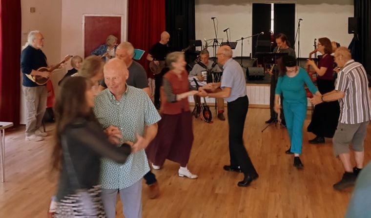 Couples dancing, with a selection of musicians playing in the background